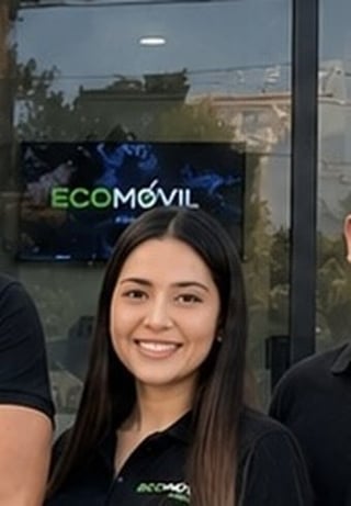 Woman in black ECOMOVIL branded shirt smiling at camera with storefront window in background